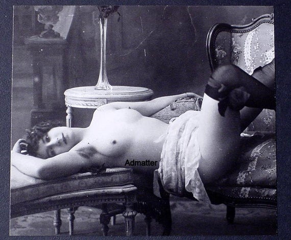 flapper reclining topless on a sofa, while wearing black stockings